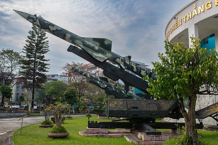 Outdoor military aircraft display on a pedestal at a Hanoi museum.