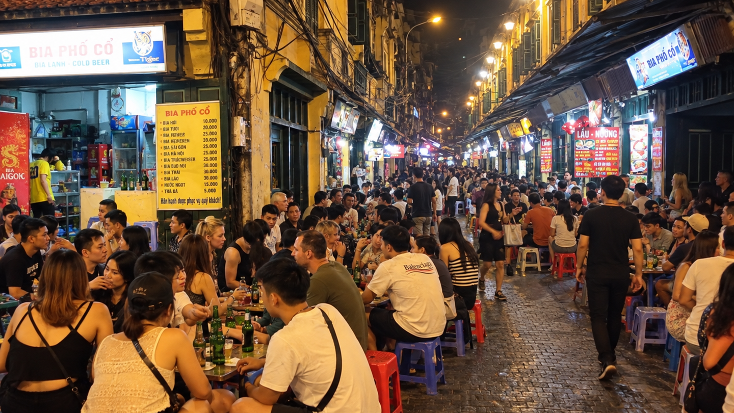 Crowded nighttime street in Hanoi's Old Quarter, lined with cafés and low sidewalk tables.