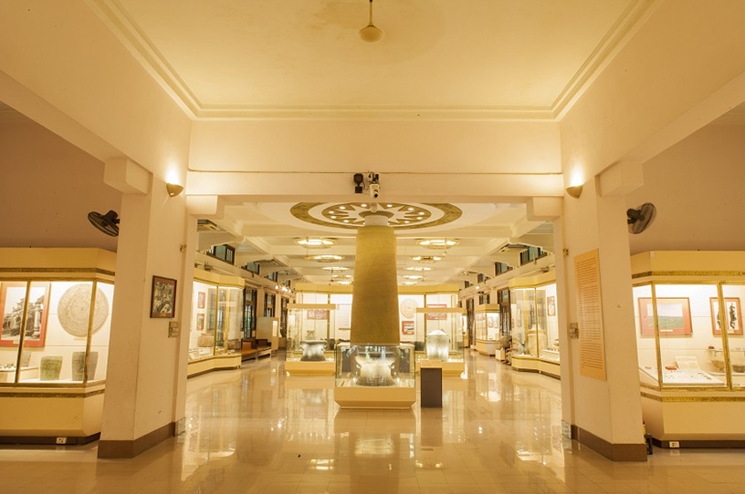 Bright interior gallery with columns and display cases at the Vietnam National Museum of History.