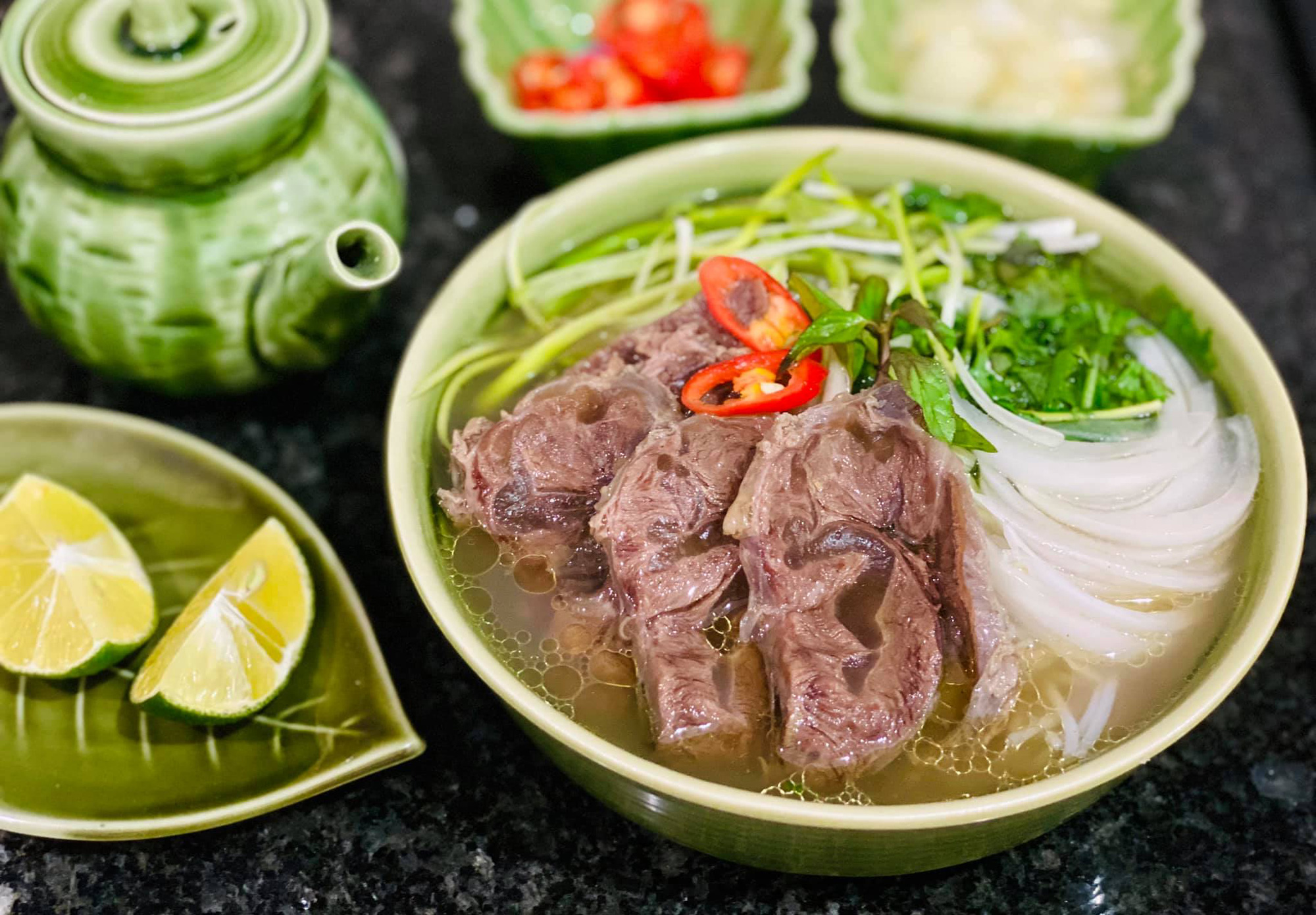 Close view of sliced beef and flat rice noodles in a bowl of pho bo.