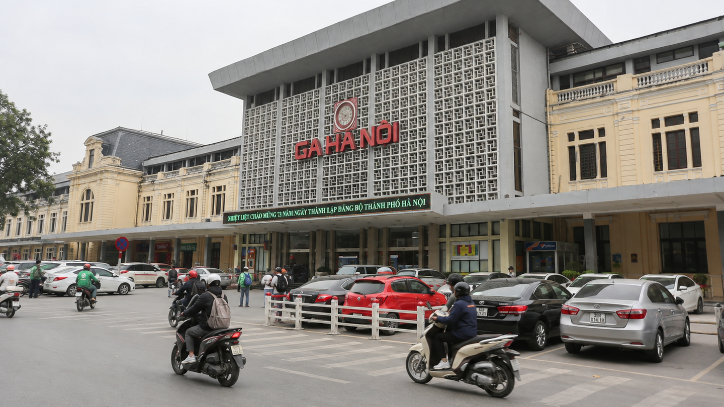 Front of Hanoi Railway Station with taxis and motorbikes outside.