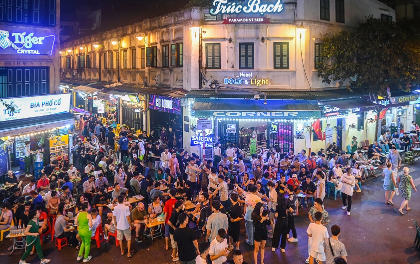 Crowded night scene on a Hanoi Old Quarter street filled with neon signs and diners.