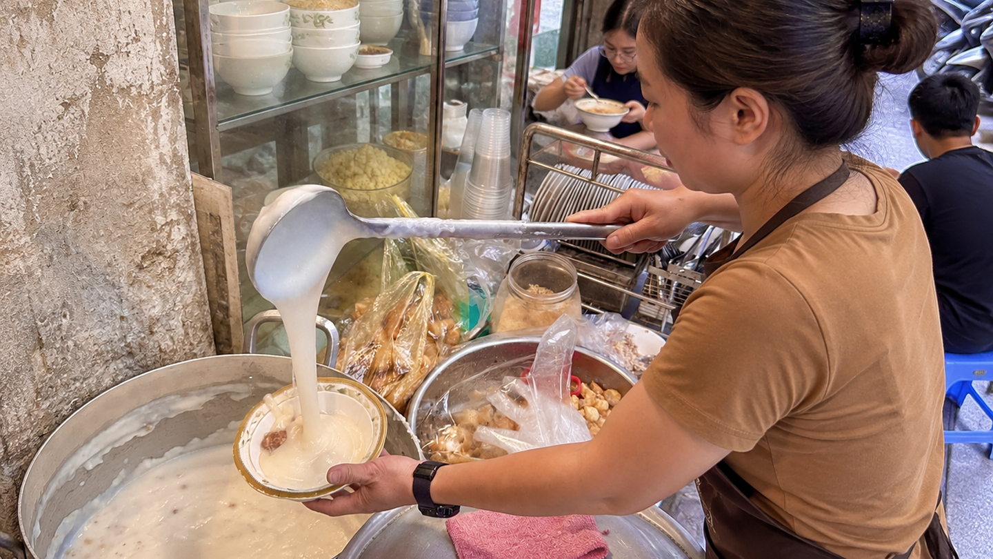 A vendor serves bowls of chao suon, pork rib rice porridge, at a Hanoi stall.