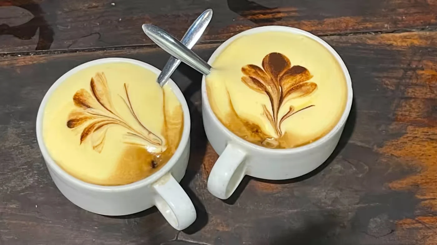 Two cups of egg coffee with leaf-shaped foam art at Cafe Lam in Hanoi.