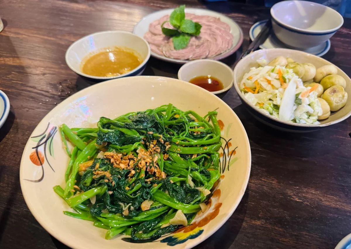 Stir-fried greens and home-style Vietnamese dishes on a wooden table at Tầm Vị.