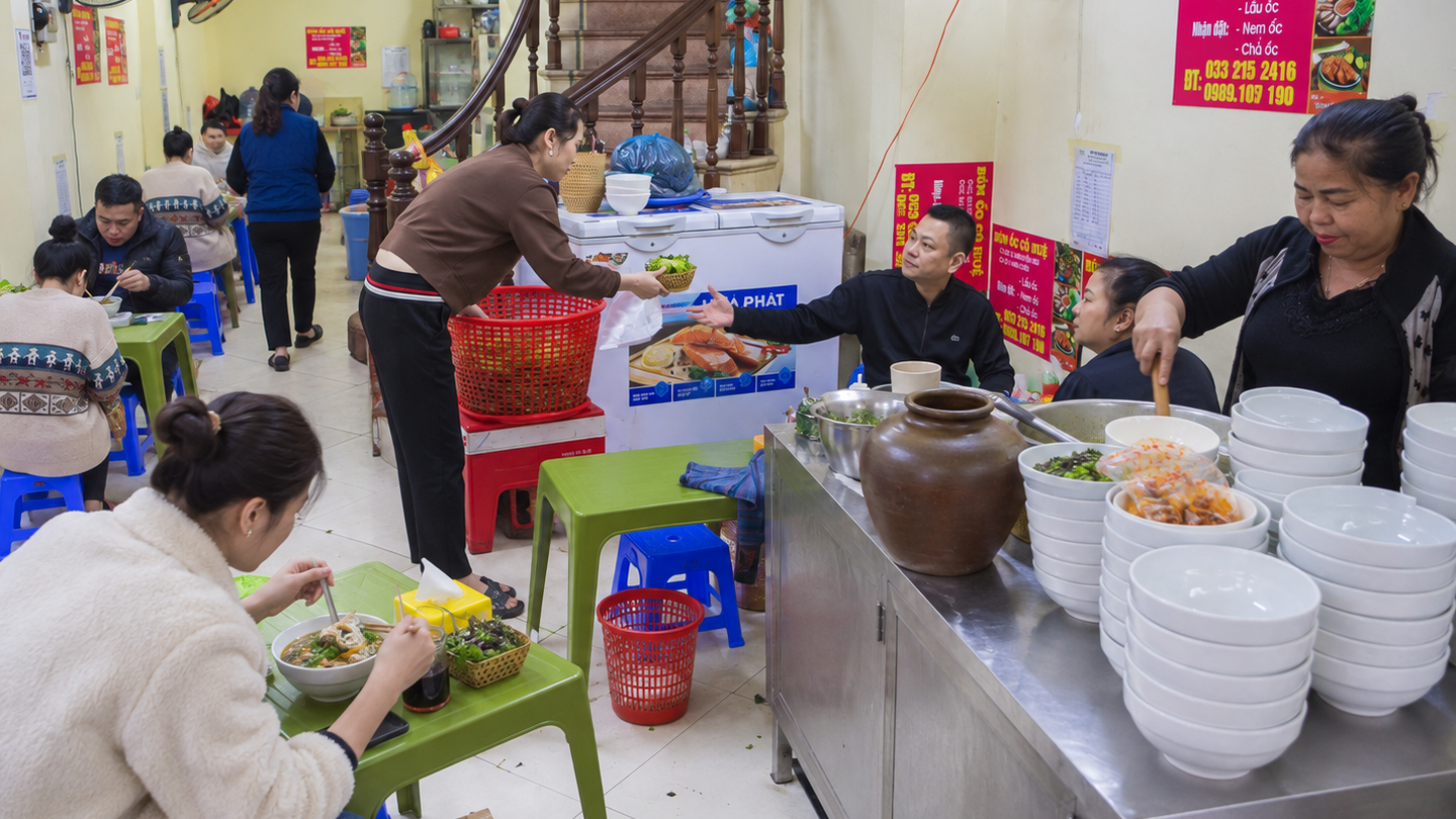 Customers eat bowls of bun oc, Vietnamese snail noodle soup, at a Hanoi street stall.
