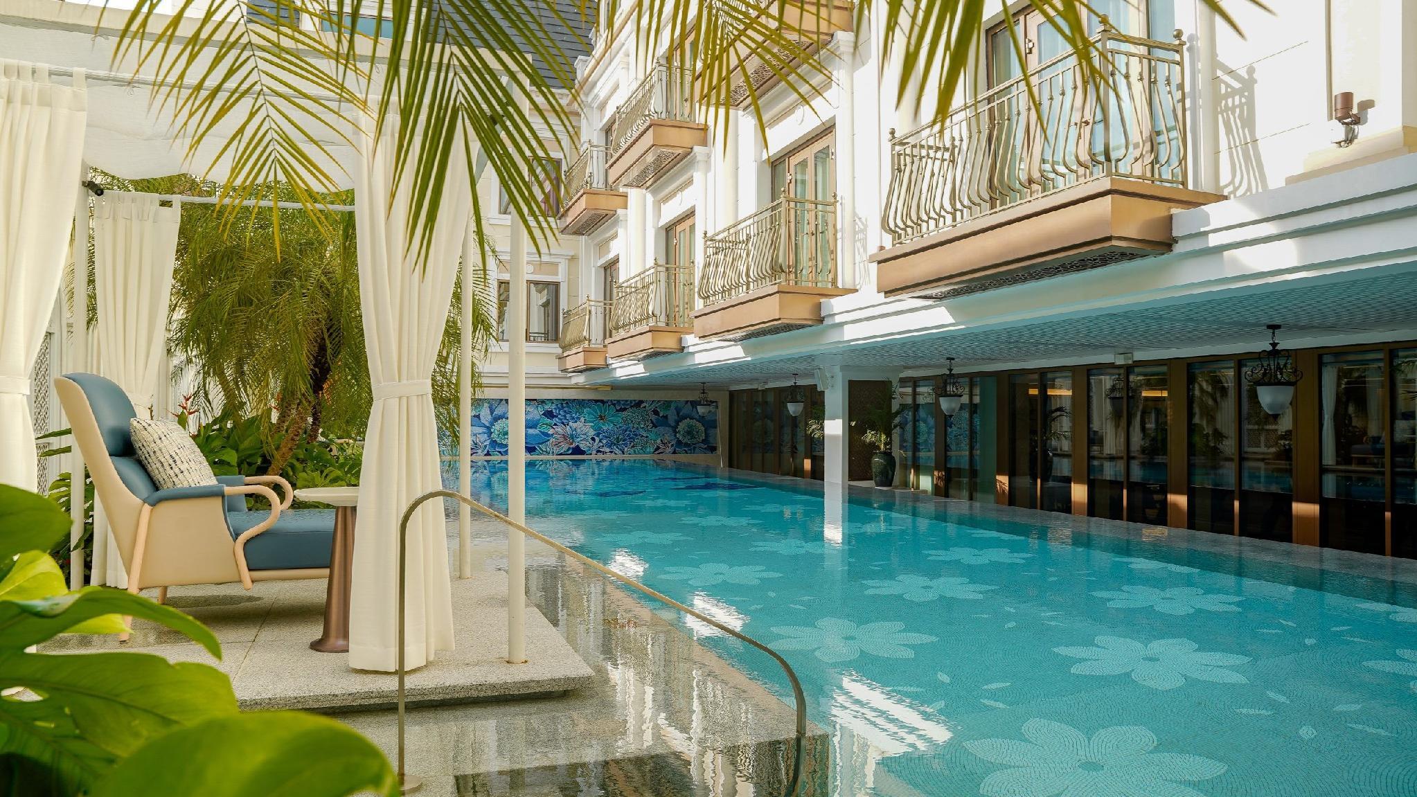 The heated outdoor pool by day, lined with cabanas and palms
