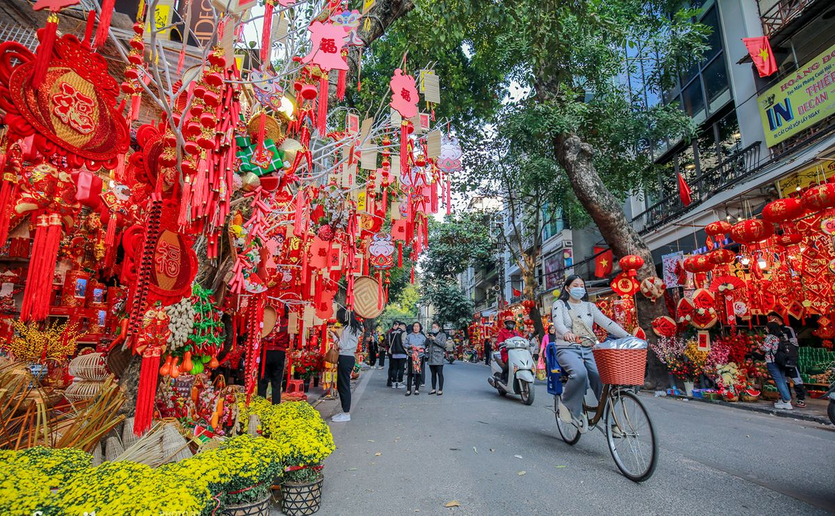 Street market decorated with red and gold Tết ornaments and lanterns in Hanoi.