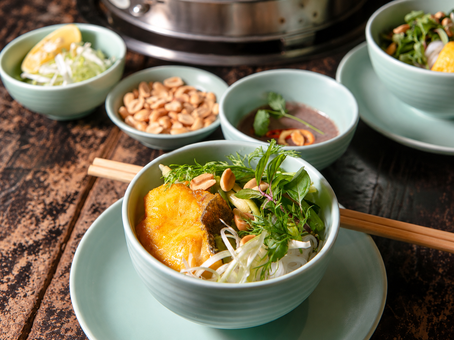 Bowl of turmeric fish with rice noodles and herbs at Chả Cá Thăng Long in Hanoi.