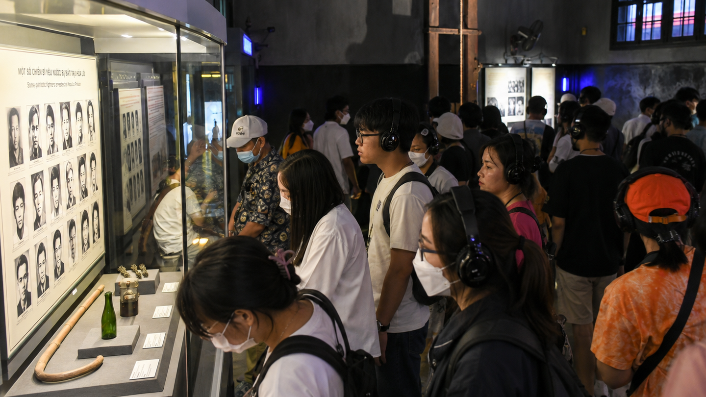 Visitors view historical photographs and displays inside a Hanoi museum gallery.