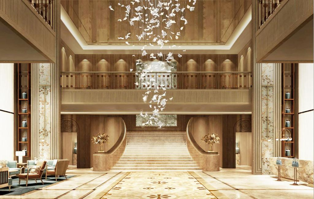 Double-height hotel lobby with a chandelier and warm wood-panelled walls.