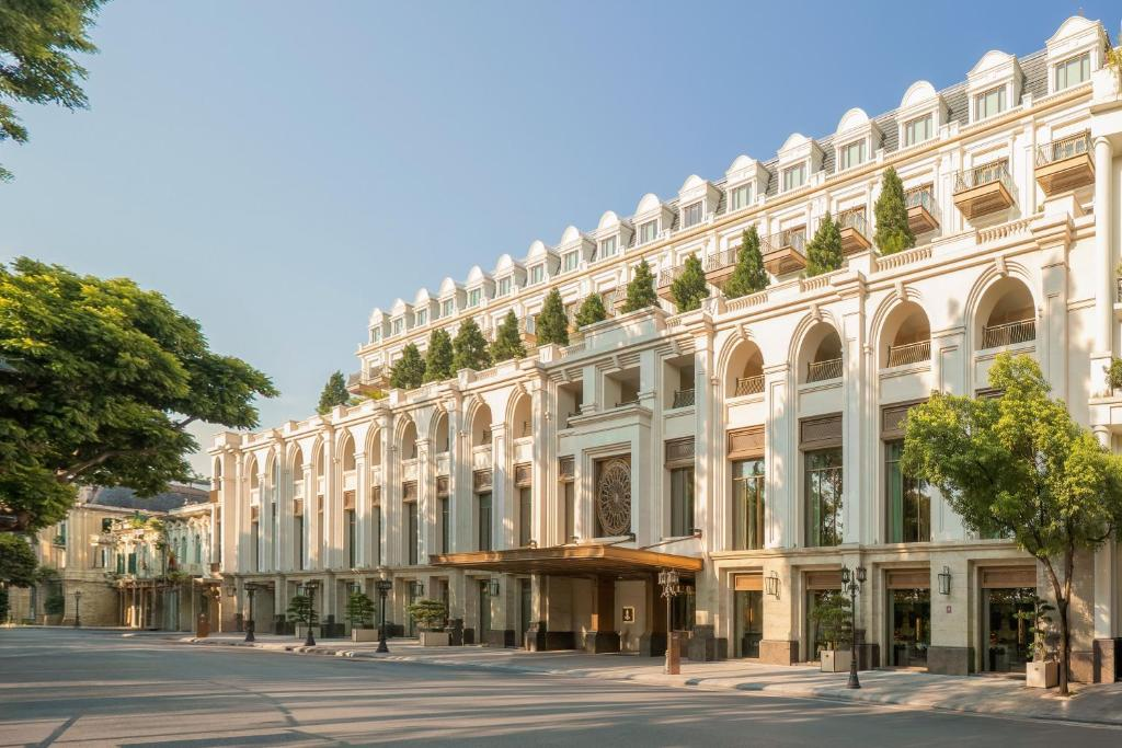 The Theodore Hanoi's pale French-style hotel facade behind a leafy street.