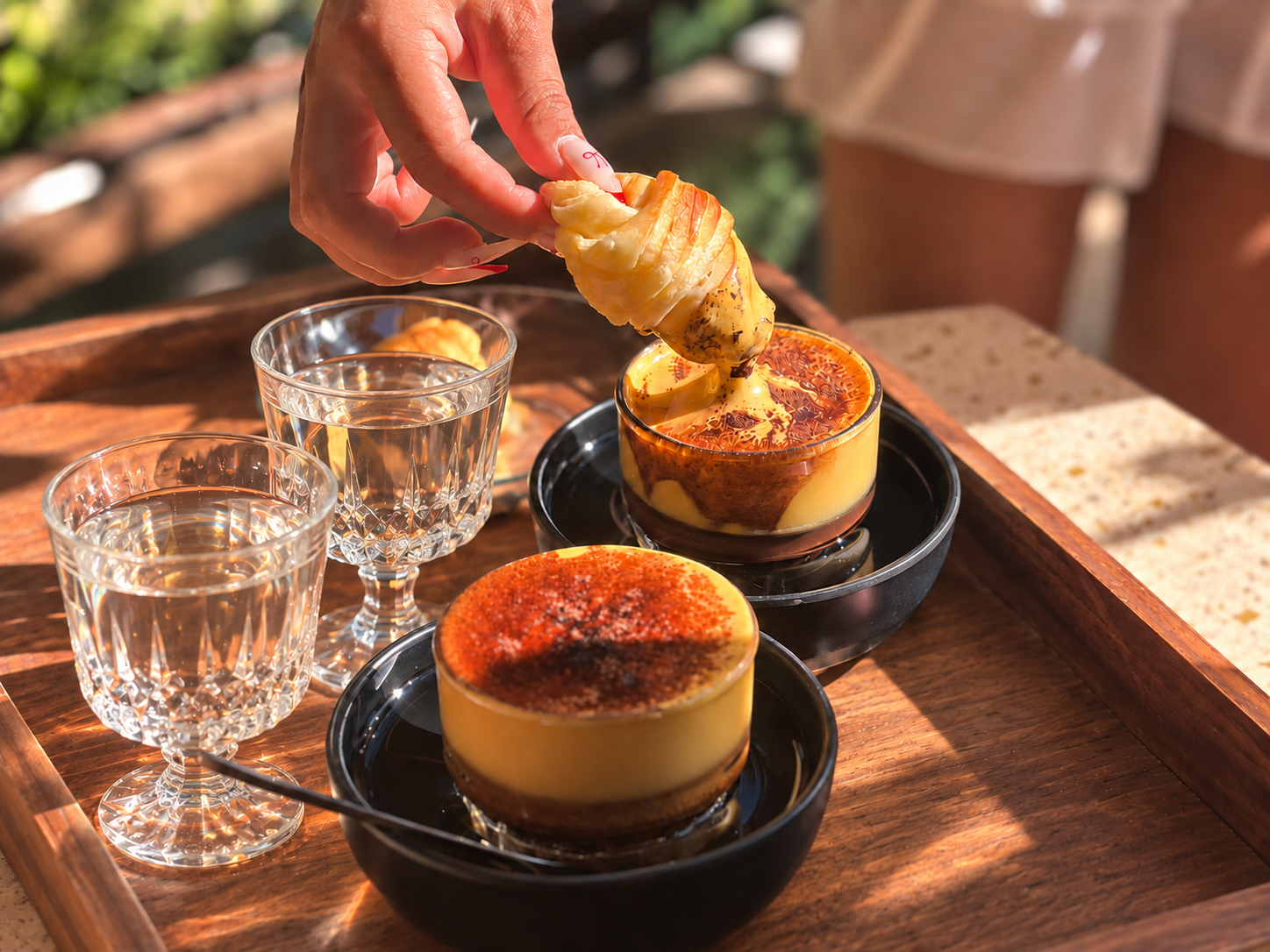 Two caramelised desserts served with iced drinks at a Hanoi café.