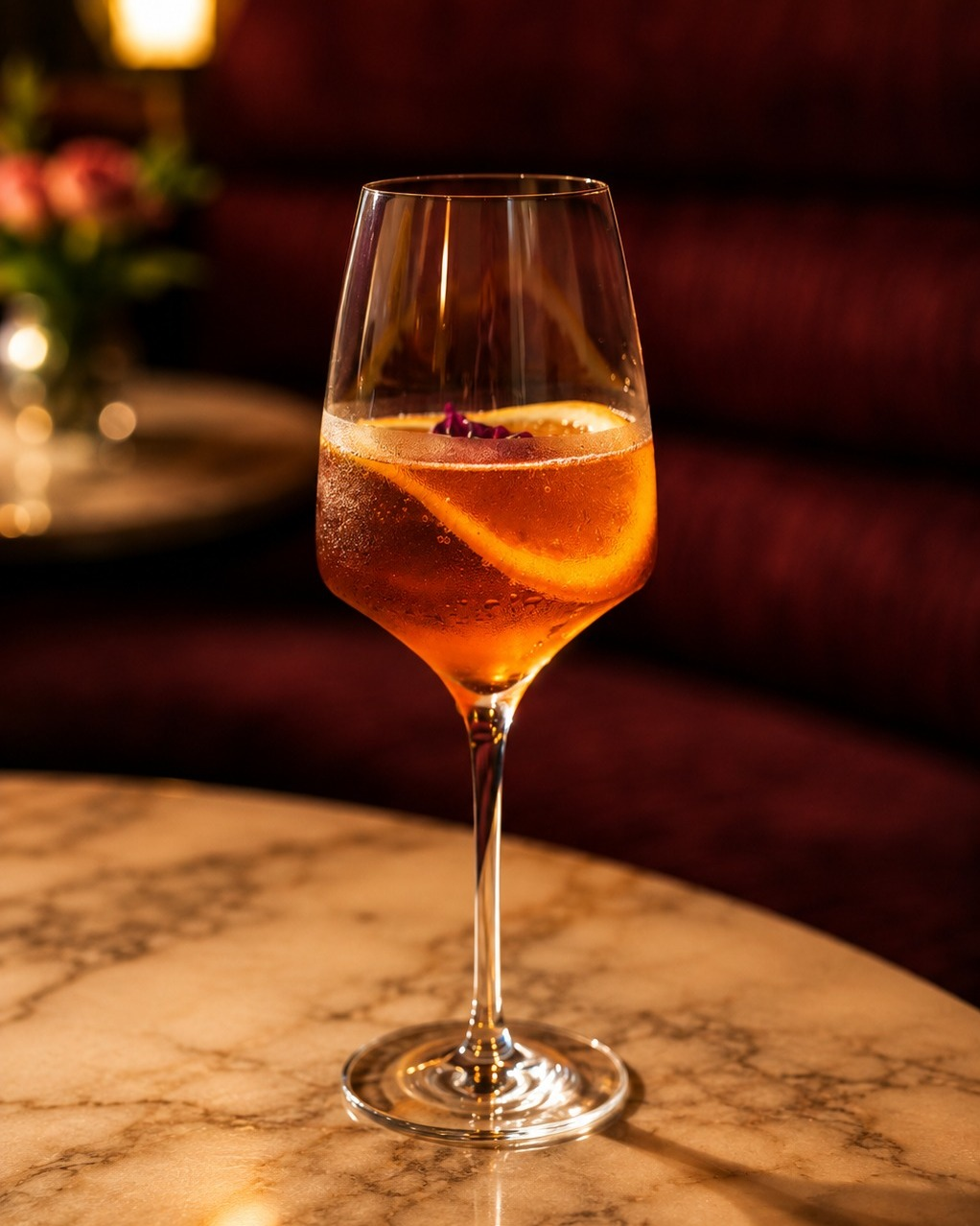 Amber cocktail served in a stemmed glass on a marble rooftop bar table.