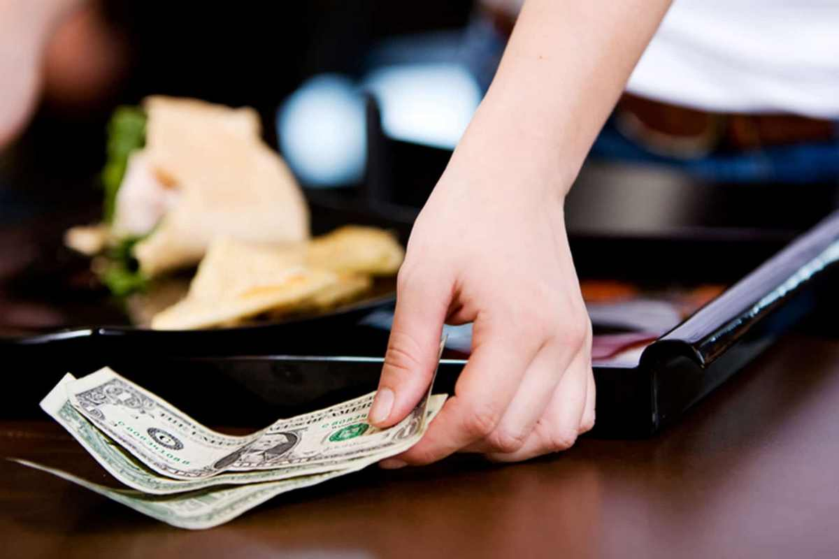 Customer places cash on a bill tray after a restaurant meal.